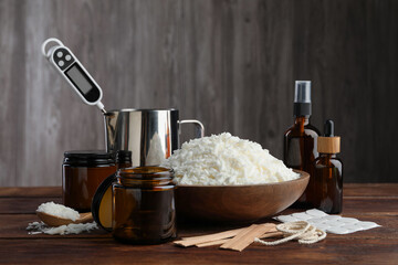 Soy wax and other supplies for making candles on wooden table
