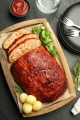 Delicious turkey meatloaf with vegetables served on black table, flat lay