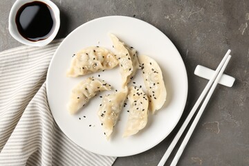 Delicious gyoza dumplings with sesame seeds served on grey table, top view