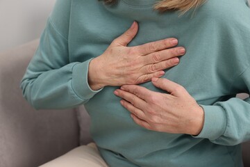 Heart attack. Senior woman suffering from pain in chest indoors, closeup