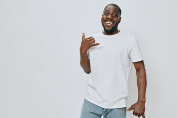 Smiling man showing hand gesture in casual white t shirt and jeans, vibrant expression with a plain...