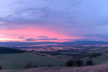 Photo - Pink and Purple Sunset Over Cityscape and Rolling Hills