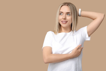 Young woman checking her breast on beige background. Cancer awareness concept