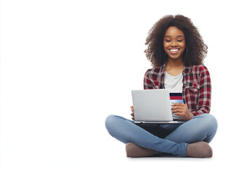 Fototapeta premium A happy woman sitting on the floor with her legs crossed, holding an open credit card in one hand and using a laptop computer to make online purchases against a white background