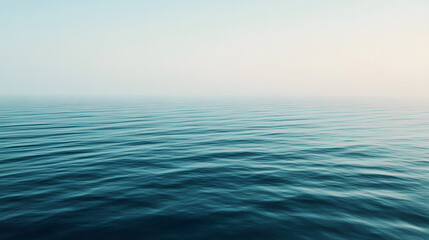 Obraz premium Blue ocean waves gently moving under a clear sky.