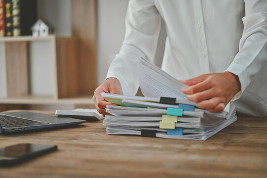 A person is holding a stack of papers on a desk