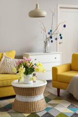 Vase with beautiful tulips and toy bunny on table in living room decorated for Easter celebration