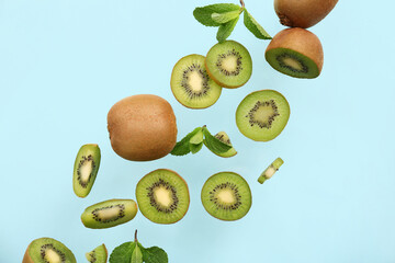 Ripe cut kiwi with mint leaves flying on color background