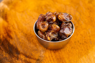 Delicious dried dates, popular fruit dates during the month of Ramadan on a round wooden board