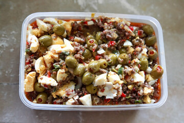 Plastic container showing argentinian empanada filling with ground beef, eggs, and olives