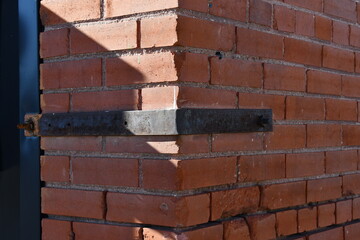 Metal bracket on corner of old brick building.
