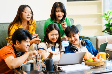 A group of young Asian college friends sitting on a sofa at home, watching a laptop, enjoying cheerful conversation and laughter, bonding over friendship, and sharing happy experiences together