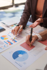 Close-up of two businesswomen working at desk discussing business strategies, analyzing financial...