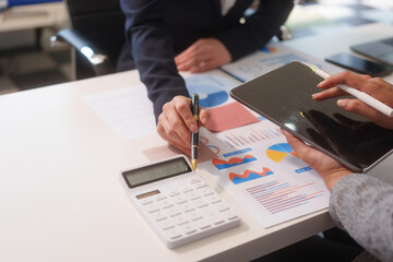 Close-up of two businesswomen working at desk discussing business strategies, analyzing financial charts, planning marketing plans and using laptop to drive business growth in professional office