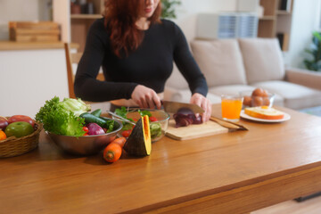 A white woman in workout clothes makes vegetable and fruit juice using a blender on the kitchen...