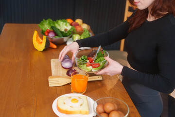 A white woman in workout clothes makes vegetable and fruit juice using a blender on the kitchen...