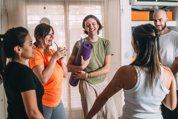 Diverse group of sporty people talking, laughing. Resting and drinking mate after yoga class in a friendly social atmosphere at the yoga club.