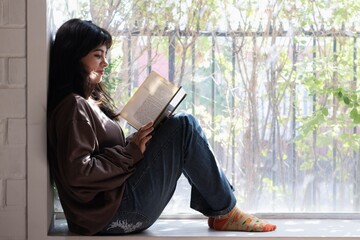 teenage girl reading a book while sitting at home