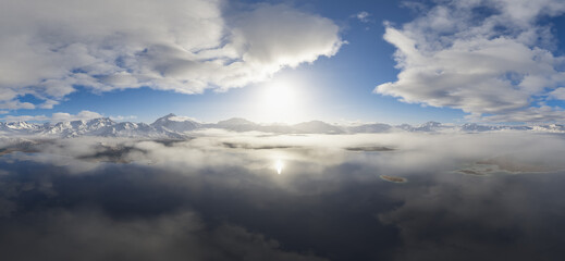 Beautiful Snow-Covered Mountains with Sunlit Clouds Reflecting on a Tranquil Lake