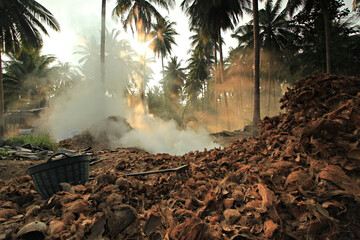 Workers scoop coconut shells enter the charcoal kiln at Thap Sakae District in Prachuap Khiri Khan