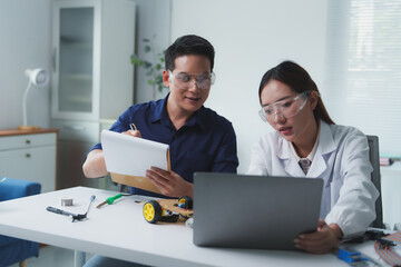 Asian engineers collaborating on a project using laptop and taking notes in modern office