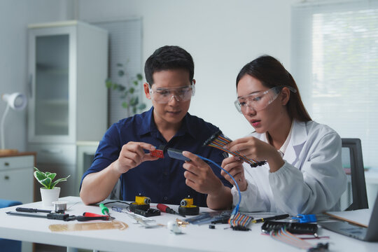 Engineers collaborating on innovative robotics project, connecting wires and components