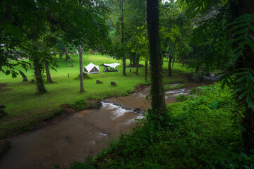 nature camping tent and family relax camp in green tree forest or jungle with red flow water stream on rainy season at Khao Laem National Park Ka Teng Cheng waterfall campground for holiday vacation