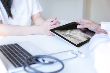 The doctor examines the patient and looks at an X-ray of the shoulder.