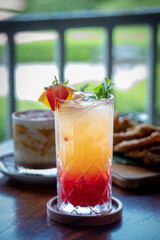 A tiramisu dessert, likely served in a glass together with tropical punch drinks and a portion of fried tempeh, tofu and bakwan on the table