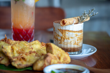 A tiramisu dessert, likely served in a glass together with tropical punch drinks and a portion of...