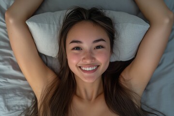Fototapeta premium A happy woman lies in bed in the morning, relaxing smiling and stretching as soft sunlight fills the room, her armpit showing and creating a cozy and relaxing atmosphere.