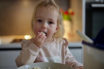 Little girl sitting at the table and eating