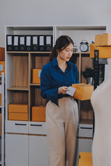Asian SME business women use laptop computer checking customer order online shipping boxes at home....