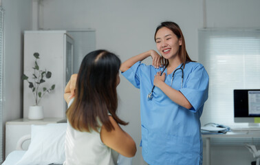 Asian doctor guiding patient doing physiotherapy exercises in clinic room