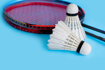 Badminton sport equipments, racket and white cream shuttlecock feather ball on blue floor, soft and selective focus.