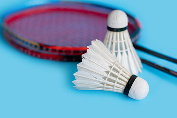 Badminton sport equipments, racket and white cream shuttlecock feather ball on blue floor, soft and...