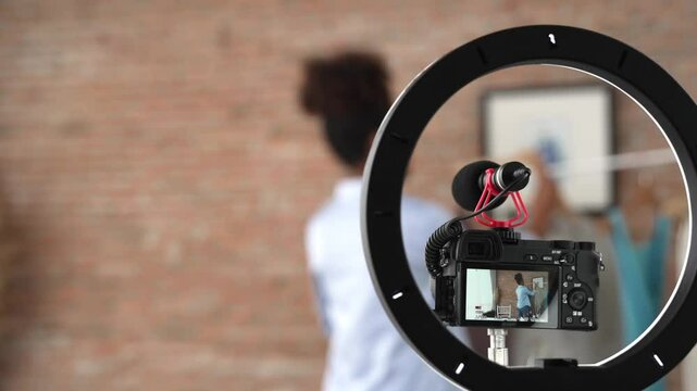 Rear view behide camera screen recording woman influencer shoot live stream vlog video review clothe crucial social media or blog. Girl with apparel studio lighting for marketing broadcasting online