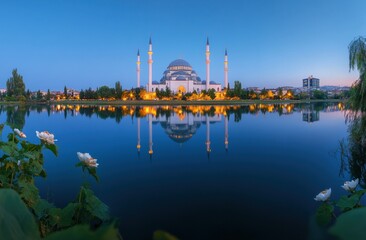 Majestic mosque reflected in tranquil lake at dawn.