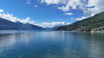 4k drone scene of emerald waters of Lake Como, with the town of Dongo in the distance in Italy