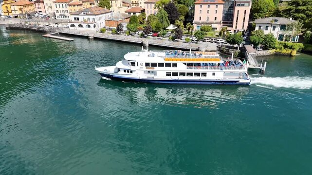 4k droone footage of a ferry boat in Lake Como, with the town of Dongo in the distance in Italy