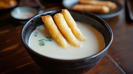 Delicious bowl of creamy soup served with crispy fried items on top.