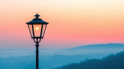 Obraz premium Streetlight at sunset with colorful sky and hills in the background. Beautiful landscape with street lamp.
