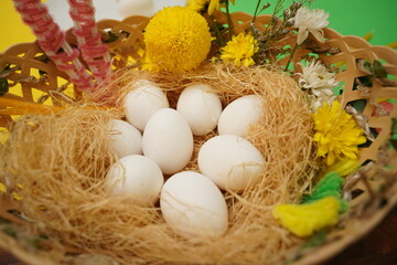 A basket with fresh eggs and vibrant flowers on a table for Easter