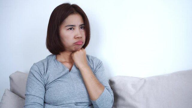 Mature Asian woman sniffing her underarms and body, worried about changes in body odor due to aging after 45