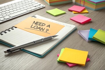 A desk with a pen and colorful paper featuring bold questions like "Need a Loan?" symbolizing brainstorming and financial planning