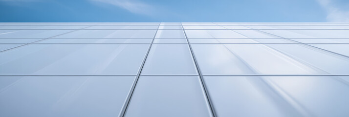 Fototapeta premium Modern building facade with reflective glass panels under clear blue sky