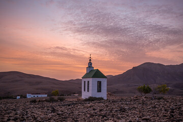 small cute white wooden chapel in a barren volcanic landscape. Sunrise, landscape shot of Ermita...