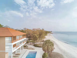 Obraz premium Beachfront resort with pool and sandy shore under a cloudy sky