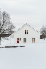 White modern house surrounded by snow in a rural setting on a cloudy winter day