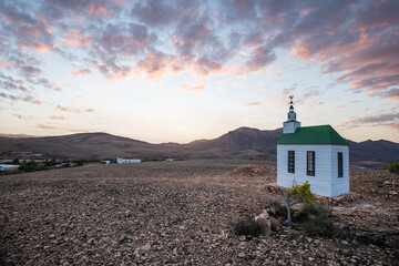 small cute white wooden chapel in a barren volcanic landscape. Sunrise, landscape shot of Ermita...